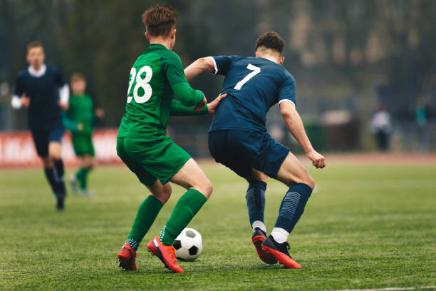 competición de fútbol para adultos. jugador de fútbol regateando una pelota y pateando una pelota durante el partido en el estadio. futbolistas en acción en el partido del torneo - soccer ball youth soccer event soccer fotografías e imágenes de stock