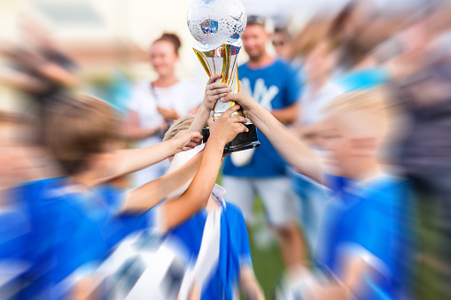 Young Soccer Players Holding Trophy. Young Sport Team with Trophy. Boys Celebrating Sports Achievement. Celebrating Soccer Football Championship. Winning team of sport tournament for kids children.