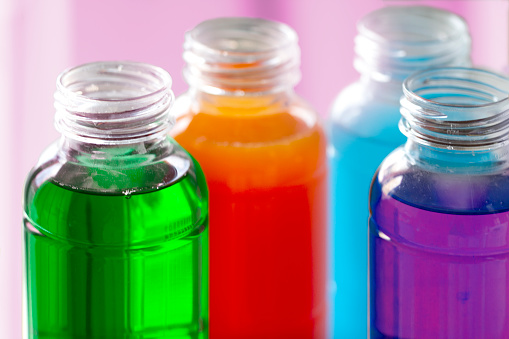 Four multicolored energy drinks and fruit juices in open bottles.