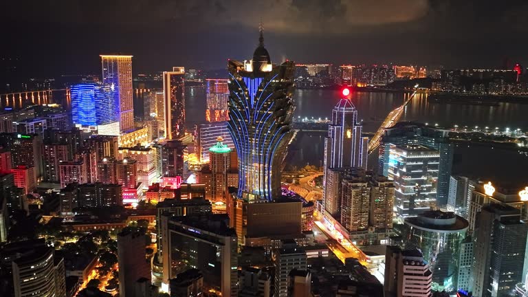 Night cityscape of Grand Lisboa Casino skyscraper building, car traffic transportation on bridge road at Macau island, drone aerial view. Asia travel landmark, wealth entertainment concept