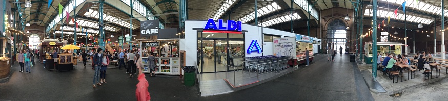 Aldi is the common company brand name of two German multinational family-owned discount supermarket chains operating over 10,000 stores in 20 countries. This branch is a worldwide exception, as it is itself completely covered once again. Photo taken from the front.