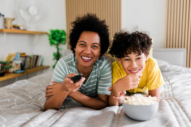 istock Mother and son watching TV and lying on bed 1558807424