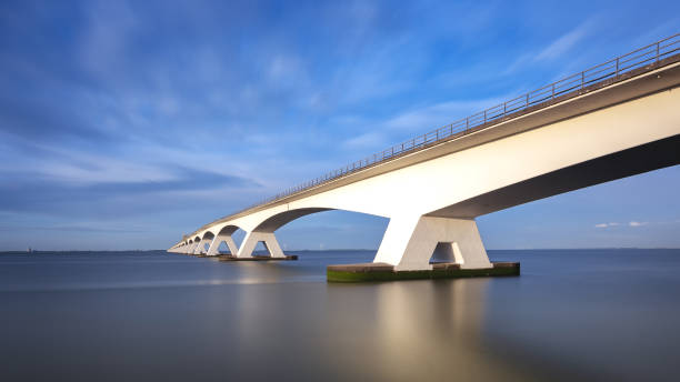istock Zeeland Bridge - long white bridge over the river, beautiful blue sky with dynamic clouds. Long time, calm water of the Oosterschelde .. 1558826634