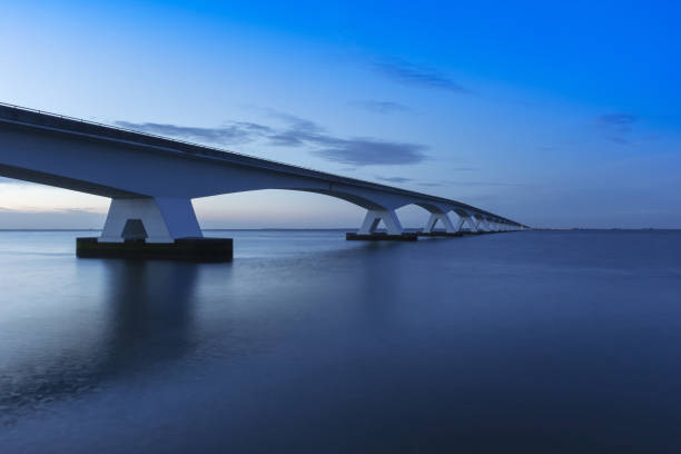 istock Zeeland Bridge - long white bridge over the river, beautiful blue sky with dynamic clouds. Long time, calm water of the Oosterschelde .. 1558827174