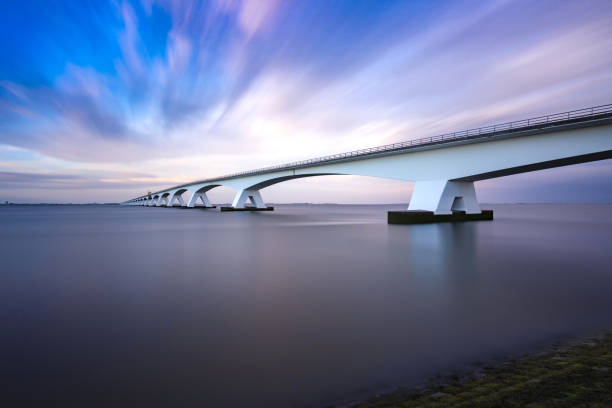 istock Zeeland Bridge - long white bridge over the river, beautiful blue sky with dynamic clouds. Long time, calm water of the Oosterschelde .. 1558827175