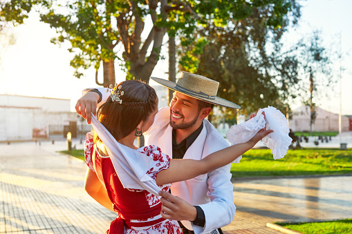 portrait latin american man hugs a woman dressed as huaso dancing cueca in the town square of La Serena