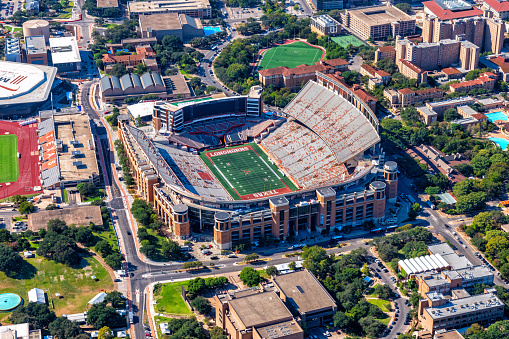 Aerial view from a helicopter of UT Football Stadium at sunset, with Austin skyline and University of Texas campus in background. All signs and logos removed - suitable for commercial use.