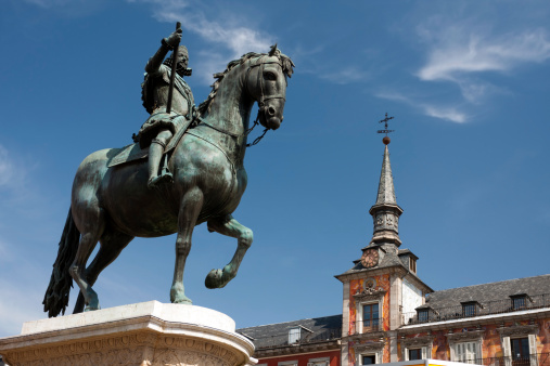 A bronze statue of King Philip III at the center of Plaza Mayor, constructed in 1616 by Jean Boulogne and Pietro Tacca, with Casa de la Panaderia visible in the background, Madrid, Spain.