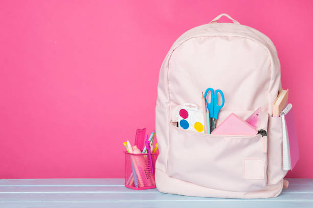 istock Pink school backpack with stationery on wooden table 1558898755
