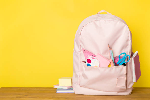 istock Pink school backpack with stationery on wooden table 1558898759