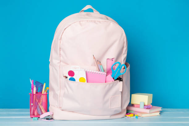 istock Pink school backpack with stationery on wooden table 1558898768