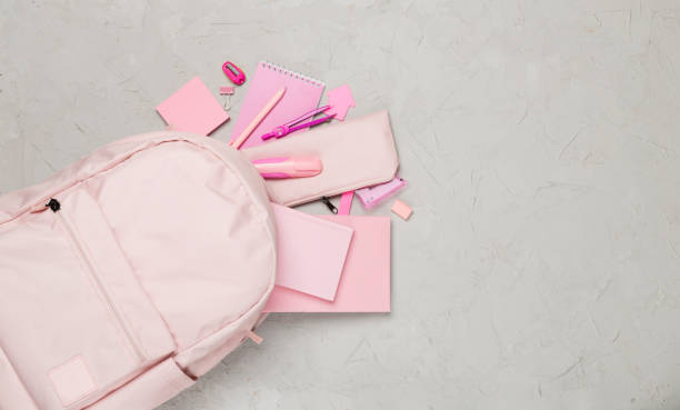 istock Pink school backpack with stationery on concrete background, top view 1558899294