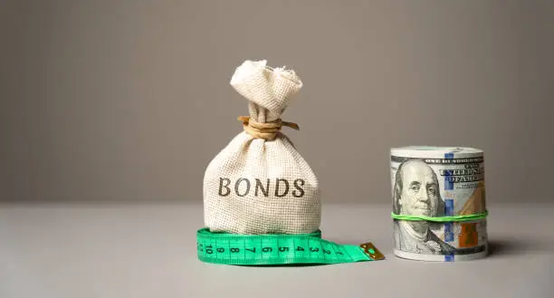 Photo of Money bag Bonds and dollars. A bond is a security that indicates that the investor has provided a loan to the issuer. Equivalent loan. Unsecured and secured bonds
