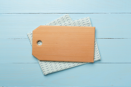 Cutting board with towel on wooden background, top view.
