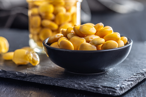 Lupini beans in brine. Pickled lupin in bowl on the black table.