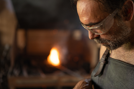 Blacksmith portrait with the forge in the background in his workshop. Blacksmith concept.