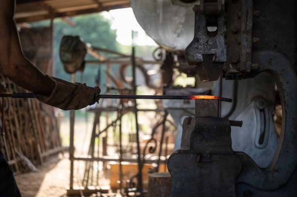 istock Close up of blacksmith hands holding a glow rod in a mechanical press in his workshop. 1558956477