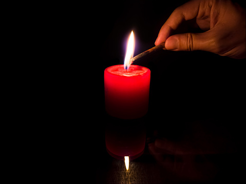 Light in the dark concept with lit candle