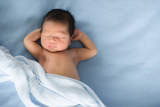 Newborn baby sleeps on blue blankets A newborn mixed race Asian Caucasian baby boy sleeps on blue blankets. With copy space biracial newborn stock pictures, royalty-free photos & images