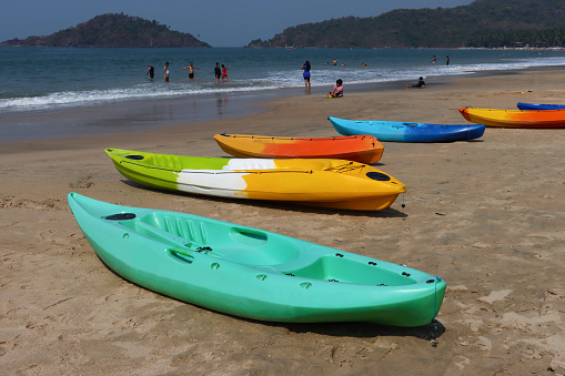 Palolem Beach, Goa, India - March, 7 2023: Stock photo showing close-up view of a row of sea kayaks available for rental on the sand of Palolem Beach in Goa, South India, a particularly popular winter holiday destination for both English and German tourists.