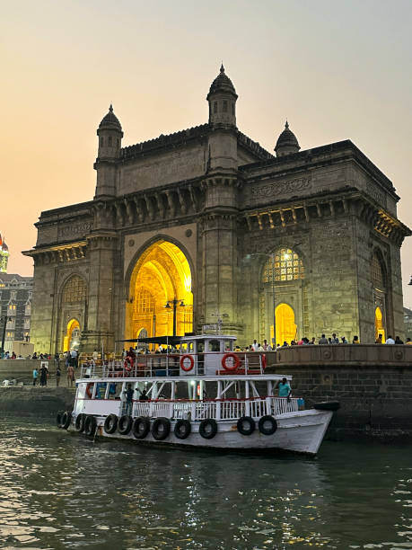 Close-up image of Gateway of India, Mumbai, India, view of Waterfront Ferry Terminal, passenger ferry at dusk, focus on foreground stock photo