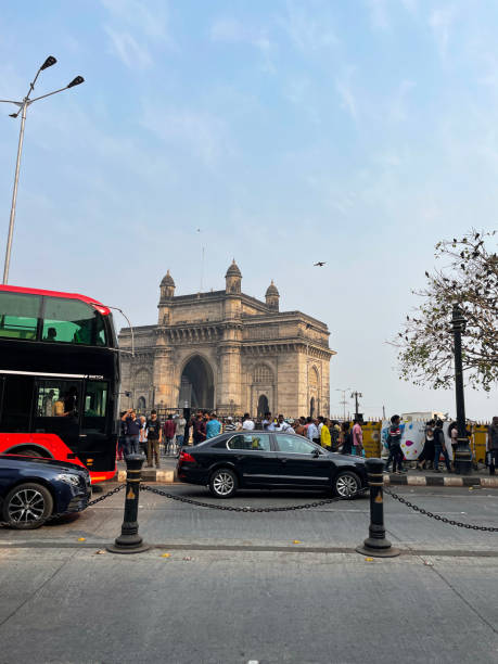 imagen de automóviles y autobuses que pasan junto a multitudes de turistas caminando por la zona peatonal de gateway of india, mumbai, india, se centra en primer plano - vertical gateway to india famous place travel destinations fotografías e imágenes de stock