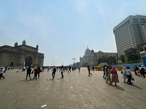 Gateway of India, Mumbai, India - March 3, 2023:  Stock photo showing tourists milling around pedestrianised area around the Gateway of India.