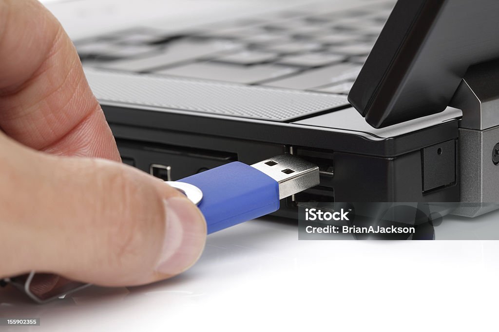 Connecting USB flash memory stick USB flash drive stick being connected to laptop computer Blue Stock Photo