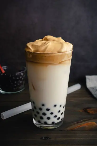 Cold dalgona coffee with milk and tapioca pearls shown with a boba straw