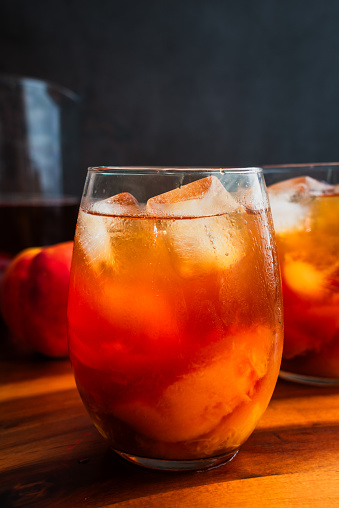 Iced tea served with slices of fresh peaches in the glasses