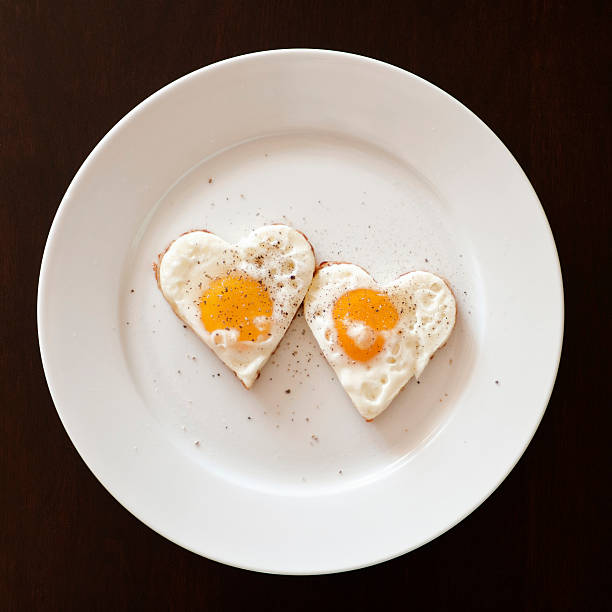 dois de coração em forma de ovos com sal e pimenta - eggs breakfast heart shape fried egg - fotografias e filmes do acervo