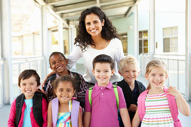 Elementary Schoolchildren Standing Outside With Teacher Group Of Elementary Age Schoolchildren Standing Outside With Teacher boy and girl looking at camera stock pictures, royalty-free photos & images