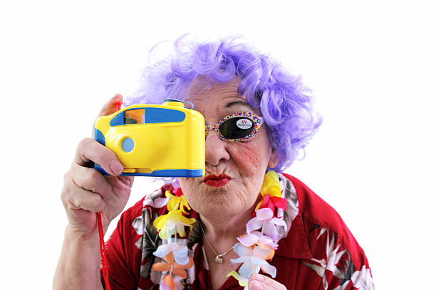 Purple haired crazy granny on white background. She's wearing a hawaiian shirt, lei, sunglasses with UV sticker and holding a toy camera. Part of a senior humor character series