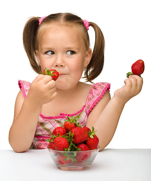 Happy little girl eats strawberries stock photo