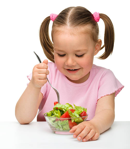 Cute little girl eats vegetable salad stock photo