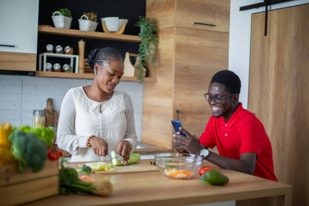 istock Young black couple taking photos with mobile phone while cooking 1559063059