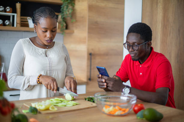 istock Young black couple taking photos with mobile phone while cooking 1559073454
