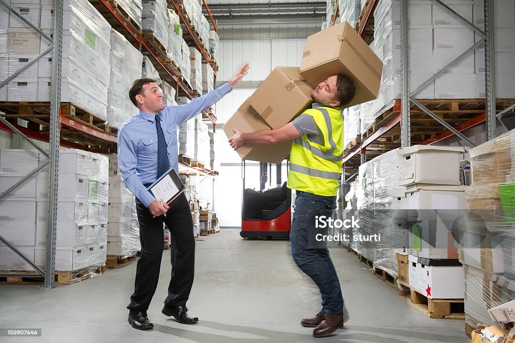 Warehouse Worker Dropping a Stack of Boxes Manager shows concern as a warehouse worker stumbles while carrying a stack of boxes. Falling Stock Photo