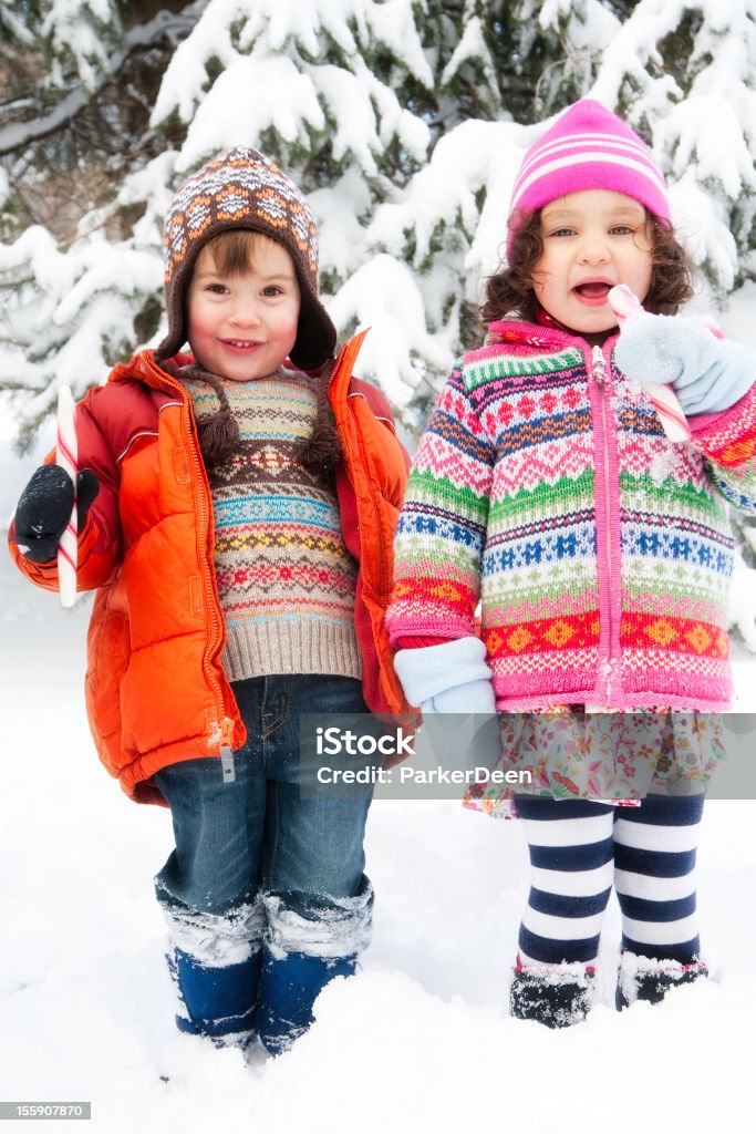 Piccola ragazza e ragazzo giocare nella neve mangiare Bastoncini di zucchero - Foto stock royalty-free di 2-3 anni