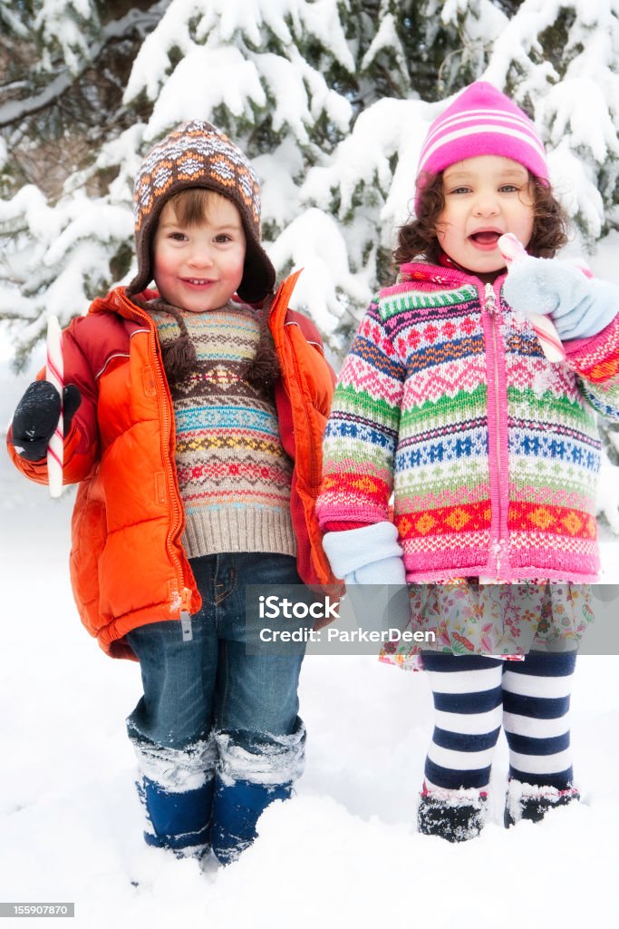 小さな女の子は雪の中で遊ぶ少年食べる杖型キャンディー - 2歳から3歳のロイヤリティフリーストックフォト