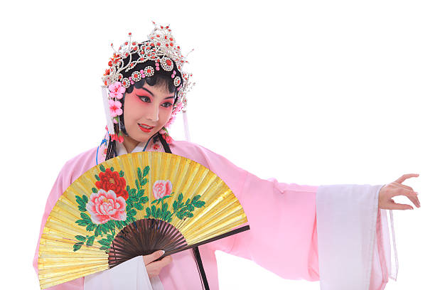 Portrait of a cheerful young Asian woman striking a dynamic pose while holding two red folding fans, performing a traditional dance for the Lunar New Year celebration.