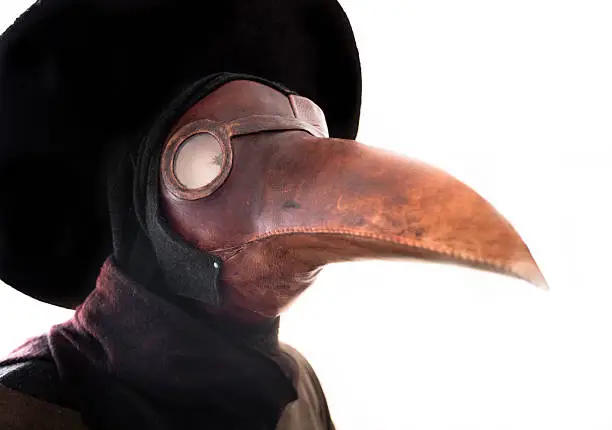 A primitive gas mask in the shape of a bird's beak. A common belief at the time was that the plague was spread by birds. It was thought that by dressing in a bird-like mask, the wearer could draw the plague away from the patient and onto the garment the plague doctor wore. The mask also included red glass eyepieces, which were thought to make the wearer impervious to evil. The beak of the mask was often filled with strongly aromatic herbs and spices to overpower the miasmas or "bad air" which was also thought to carry the plague. At the very least, it may have served a dual purpose, also dulling the smell of unburied corpses, sputum, and ruptured bouboules in plague victims.