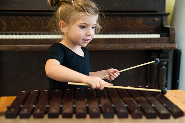 遊ぶ少女木琴、ピアノを背景にし、水平ます。 - xylophone ストックフォトと画像