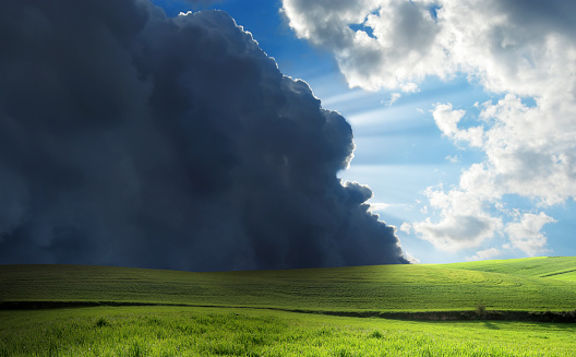 green field over stormy clouds and sunbeam. 