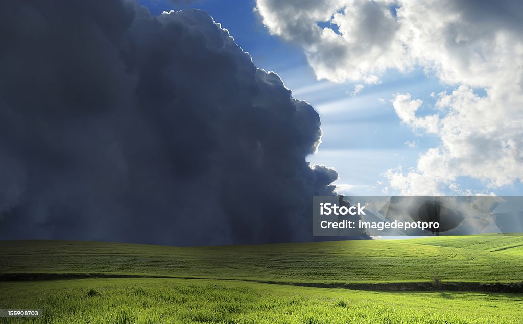 mother nature green field over stormy clouds and sunbeam.  Storm Stock Photo