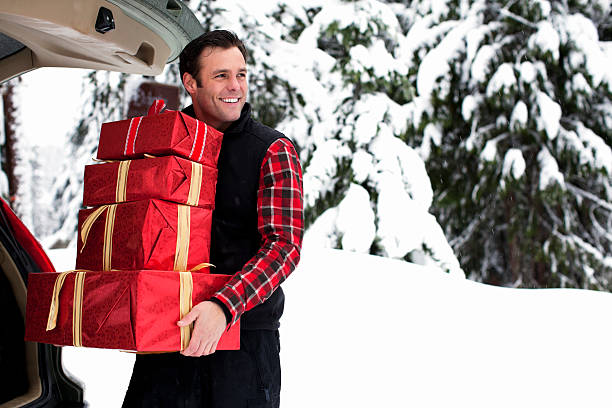 美しいクリスマスギフトを運ぶ男トランクにスノーイー日 - christmas stack gift carrying ストックフォトと画像