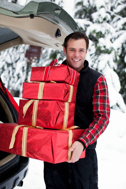 istock Beautiful Smiling Man Lifting Christmas Presents from Trunk in Snow 155908784