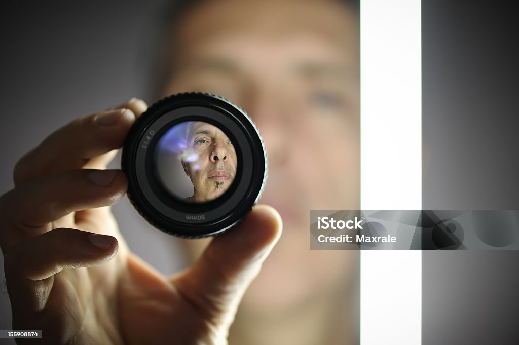 A view of a man looking through a camera lens Portrait of an older man with a neon light through the lens Sharp Stock Photo