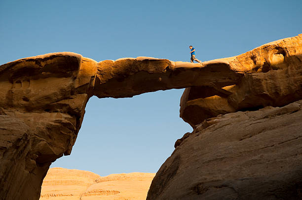 A man jogging across a natural bridge in Wadi Rum, Jordan