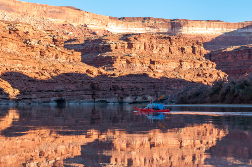 Mature woman paddling glass calm Green River in Stillwater Canyon